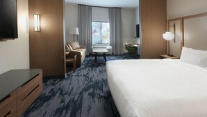 A hotel room with a large bed, a desk, a chair, a small table, a TV, and a window with curtains. - Fairfield Inn & Suites By Marriott Norfolk (Norfolk)