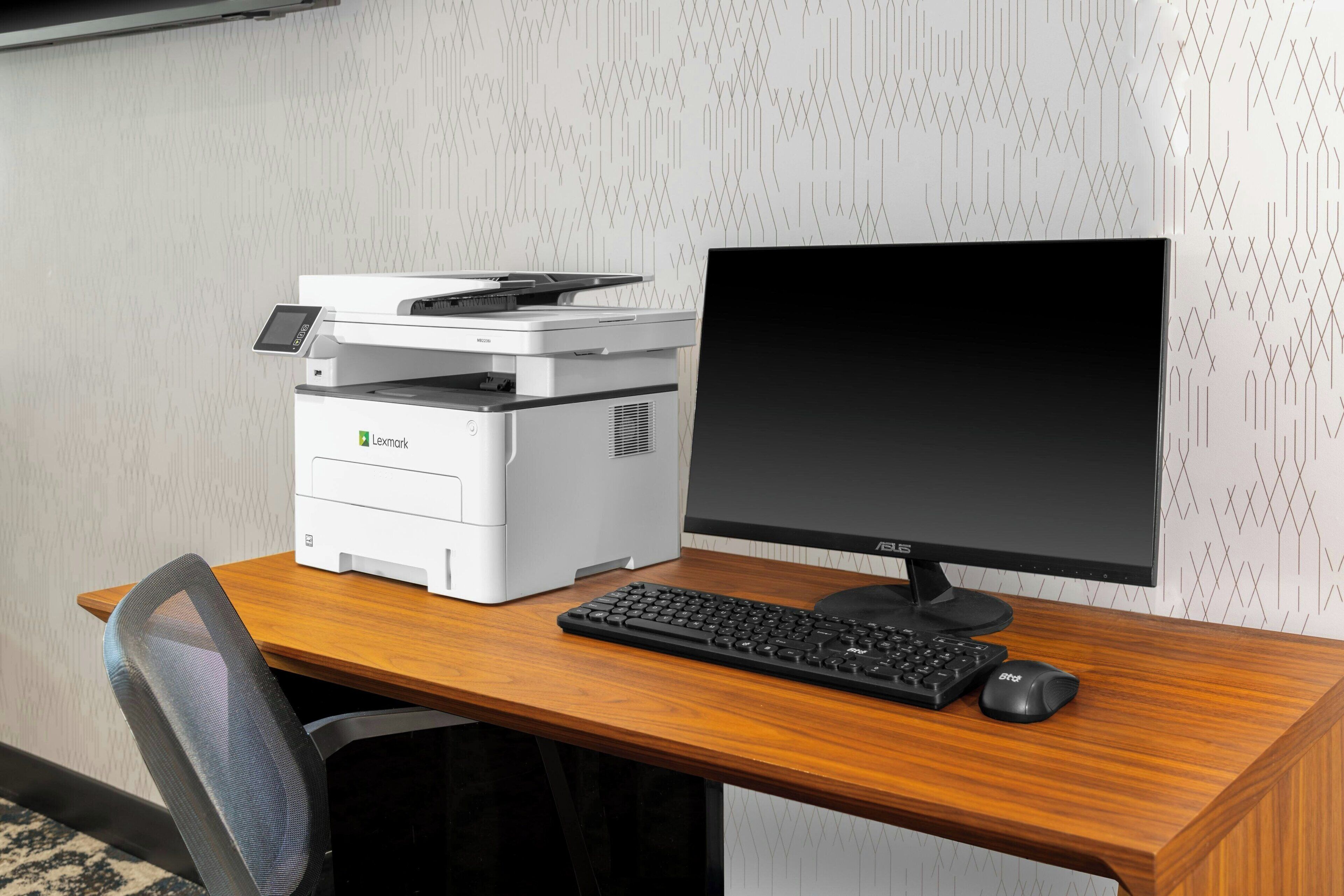 A wooden desk with a printer, keyboard, and monitor.