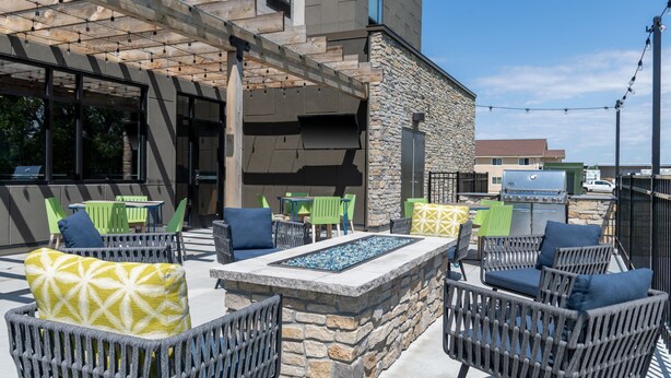 An outdoor seating area with wicker chairs and a stone fire feature. - Towneplace Suites By Marriott Norfolk (Norfolk)