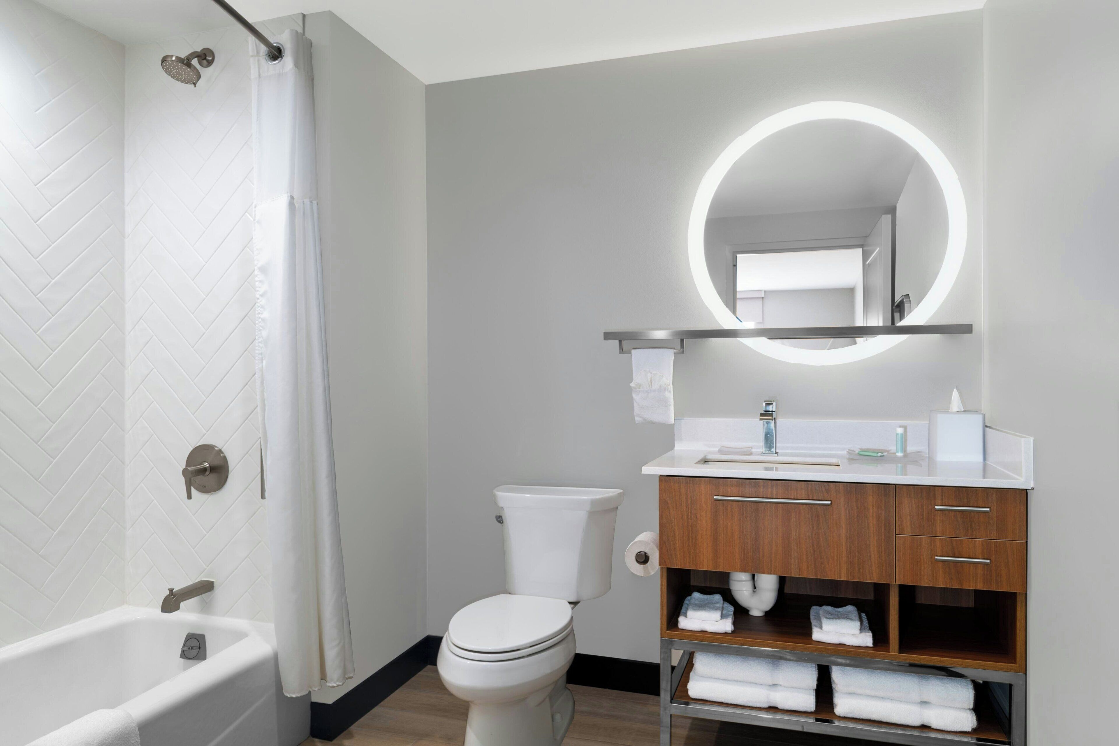 Een moderne badkamer met een badkuip, toilet en wastafel met spiegel.