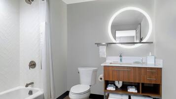 Een moderne badkamer met een badkuip, toilet en wastafel met spiegel.