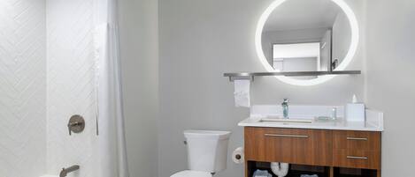 A modern bathroom with a bathtub, toilet, and vanity with a mirror.