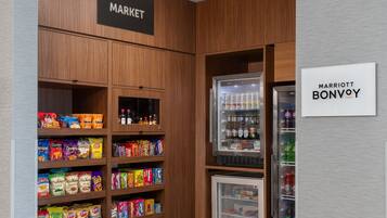 A hotel market area with shelves stocked with snacks and a refrigerated section with beverages.