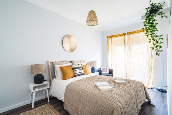 Une chambre à coucher moderne avec un grand lit, des lampes de chevet, un élément de décoration circulaire fixé au mur et une plante suspendue.
