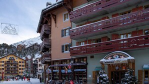 Un hotel de varios pisos con balcones, un reloj y un cartel que dice "HOMET AT THE GLACIER".