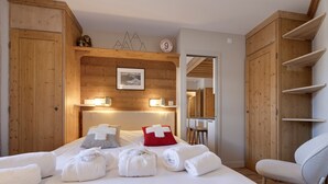 Un dormitorio con paredes de madera, una cama con sábanas blancas y una silla.
