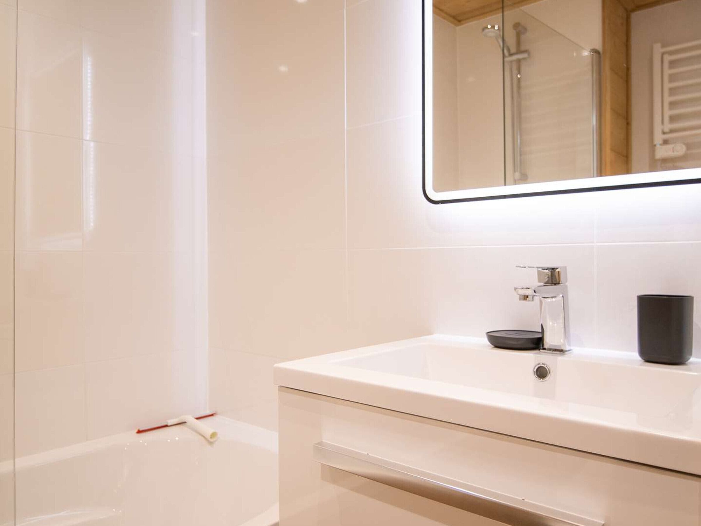 Een moderne badkamer met een wit wastafel, een spiegel en een douche.