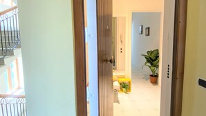Um corredor com porta de madeira, escada e planta em vaso.