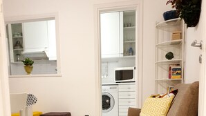 Uma sala de estar moderna com uma poltrona marrom, uma almofada amarela estampada, um sofá branco e um chão com padrão hexagonal.