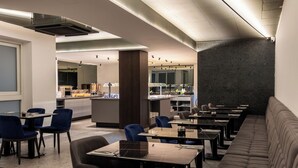 Um restaurante moderno com um balcão comprido, cadeiras azuis e um sofá.
