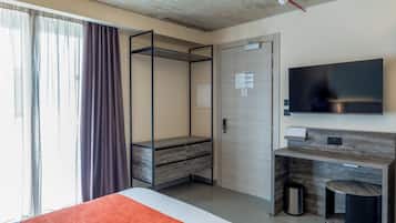 A modern hotel room with a bed, a desk, a TV, and a wardrobe.