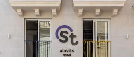 The exterior of the St. Alavits hotel with a modern facade, two balconies with metal railings, and a clear view of the entrance.