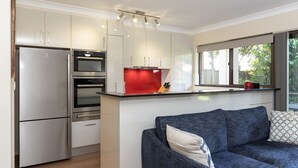 A modern kitchen with stainless steel appliances, a red backsplash, and a large window overlooking greenery. - Wallis Gardens 11 - short stroll to beautiful Wallis lake (Forster)