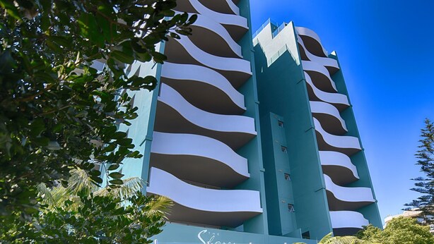 Et højt hotel med en karakteristisk bølget facade og altaner.