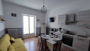 A compact living space with a dining area, kitchenette, and a yellow sofa. - Michelangelo - spacious apartment with view in La Morra  (Piemonte)