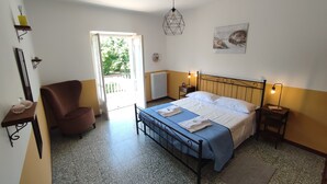 A bedroom with a bed, a chair, a bedside table, a lamp, a mirror, and a window. - Michelangelo - spacious apartment with view in La Morra  (Piemonte)