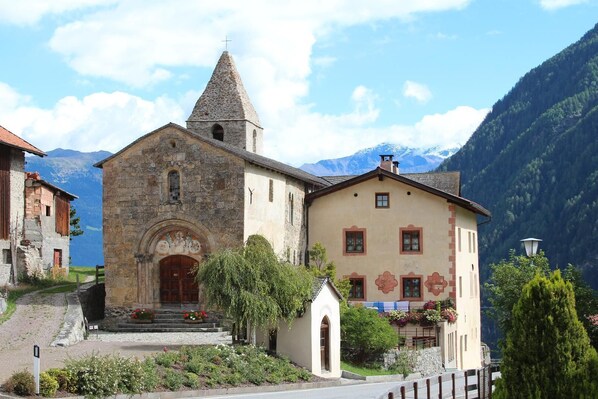 A church with a stone bell tower and a traditional building with a gabled roof.