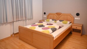 A neatly arranged bedroom with a wooden bed, a bedside table, and a nightstand.