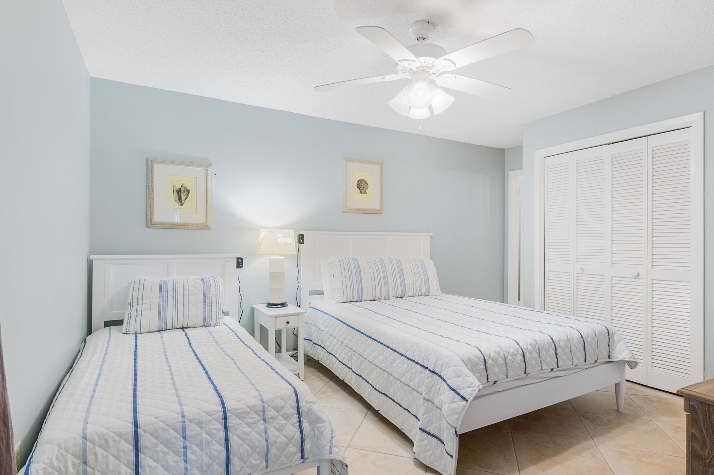 A bedroom with two beds, a ceiling fan, and a wardrobe.