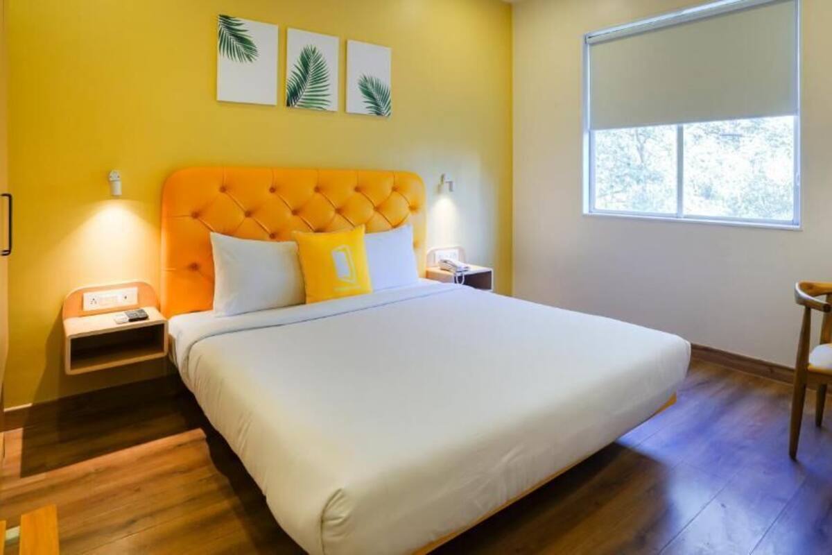 Une chambre à coucher avec un grand lit, une table de chevet, une commode, une chaise et une fenêtre.