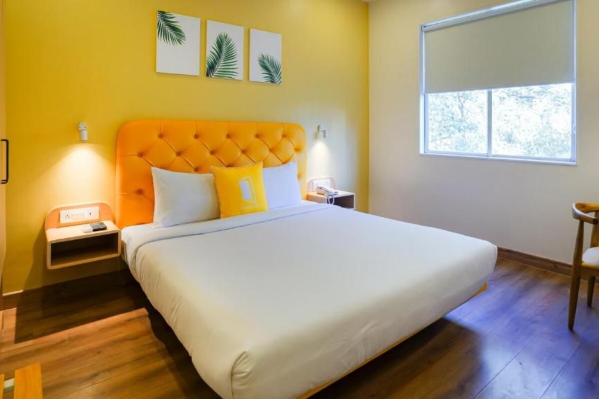A bedroom with a large bed, a bedside table, a nightstand, a chair, and a window.
