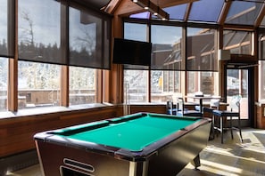 A pool table in a room with large windows, wooden walls, and a TV mounted on the wall. - Beaver Run. Ski-In Ski-Out. Unbeatable Amenities. (Breckenridge)