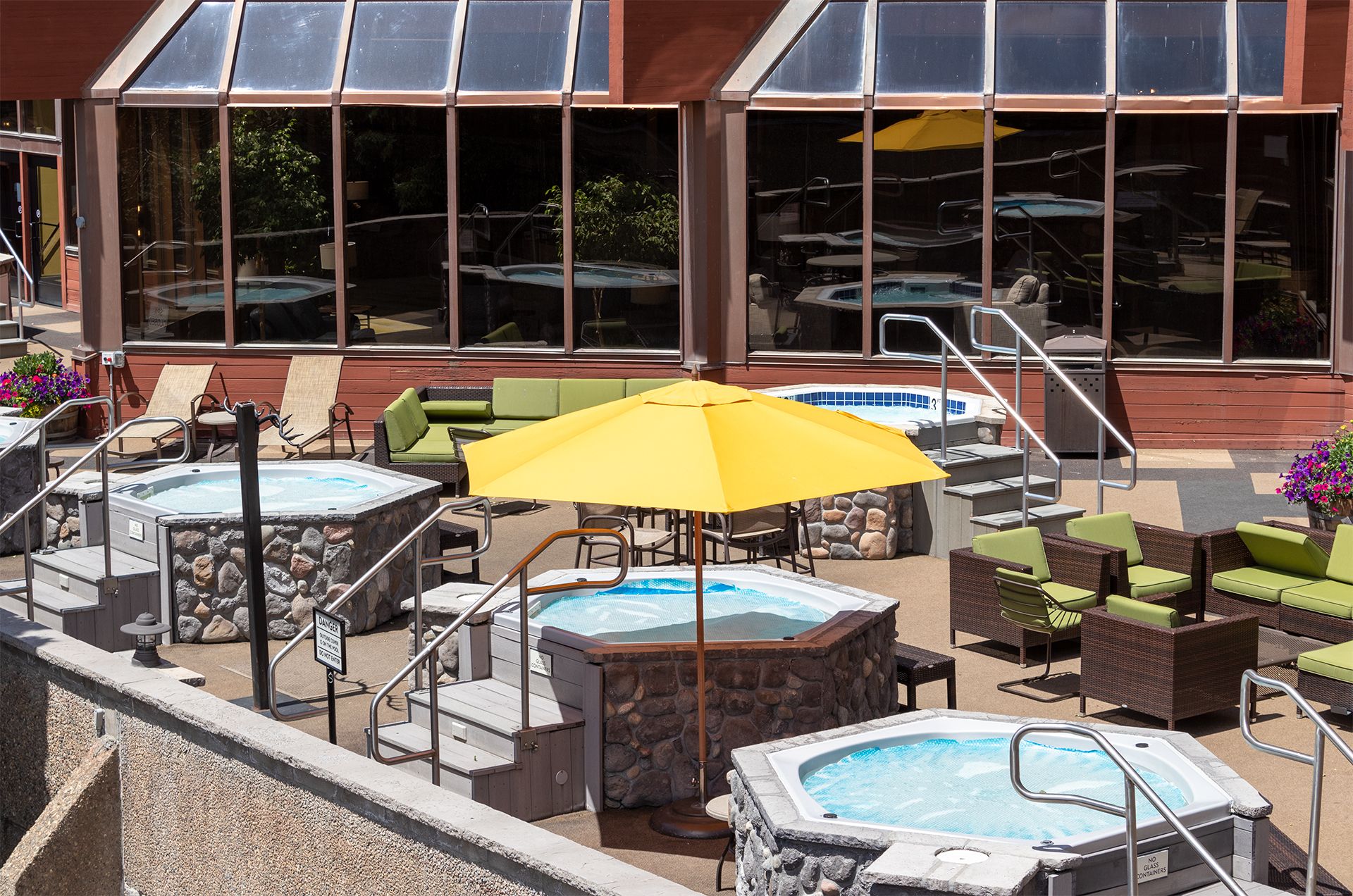 Un espace piscine extérieur comprenant des bains à remous, des chaises longues et des parasols.