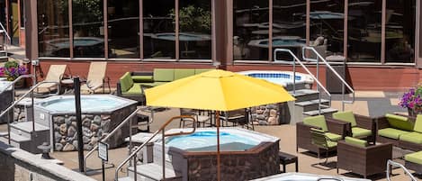 An outdoor pool area with hot tubs, lounge chairs, and umbrellas.