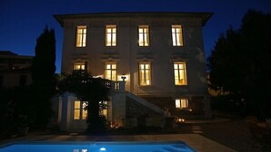 A large building with multiple windows illuminated at night, a swimming pool in the foreground, and a staircase leading to the entrance. - Stunning Belle Epoque Villa in the heart of Cannes, private pool, secure parking (Cannes)