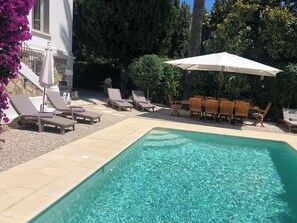 Ein Swimmingpool mit Liegestühlen und einem Tisch mit Sonnenschirmen.