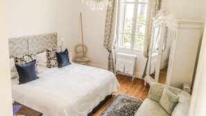 A bedroom with a large bed, a chair, a mirror, and a window with curtains. - Stunning Belle Epoque Villa in the heart of Cannes, private pool, secure parking (Cannes)