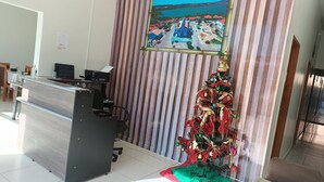 Ein Empfangsschalter mit einem Computer, ein gerahmtes Bild einer Küstenstadt und ein Weihnachtsbaum mit Dekorationen.