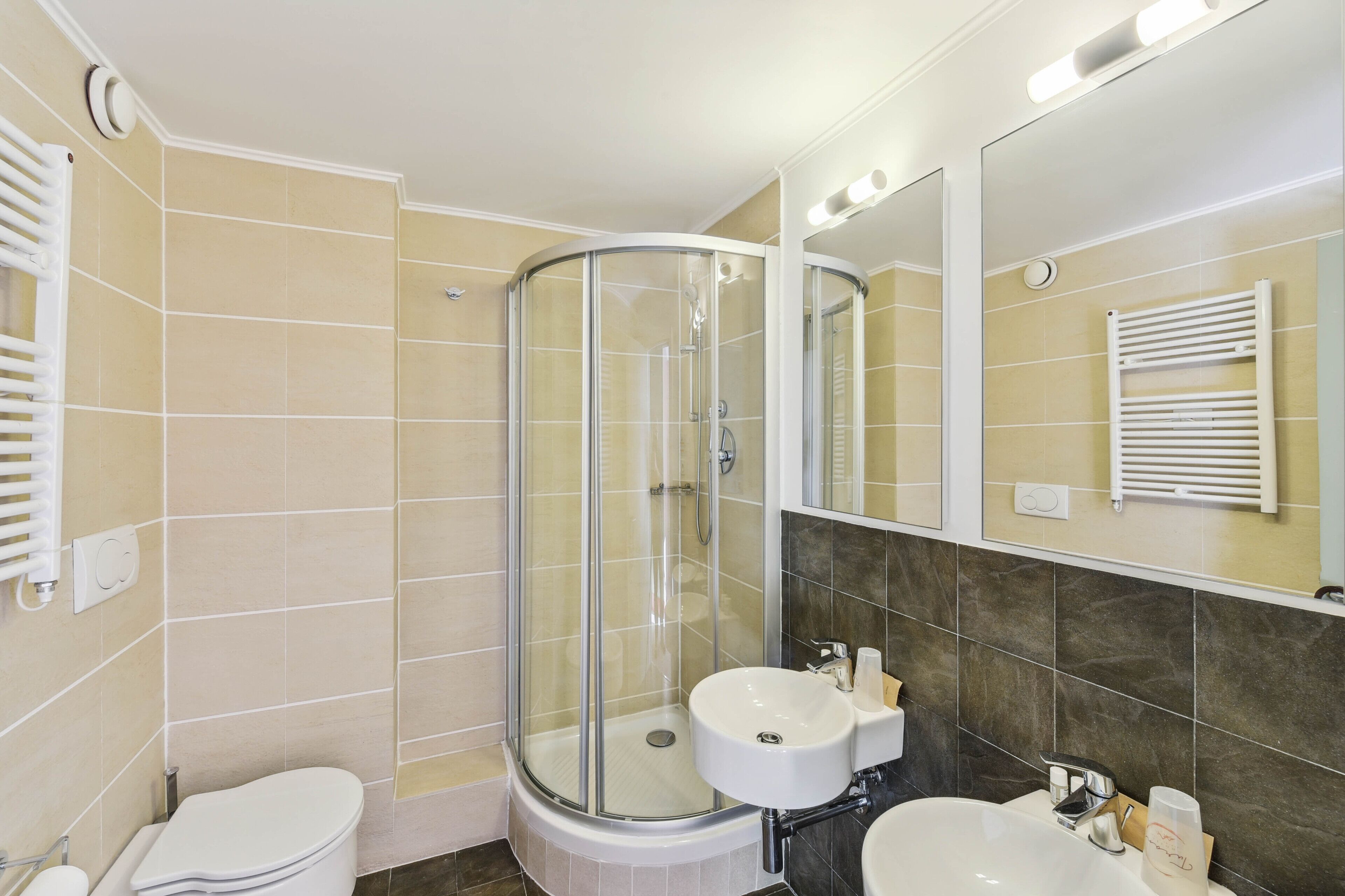 A modern bathroom with a glass-enclosed shower, a white sink, and a mirror.
