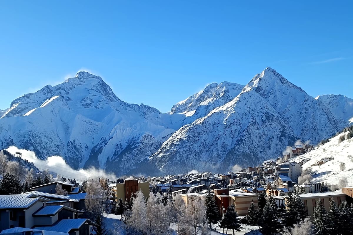 Eine verschneite Bergstadt mit Häusern und einem Skigebiet.