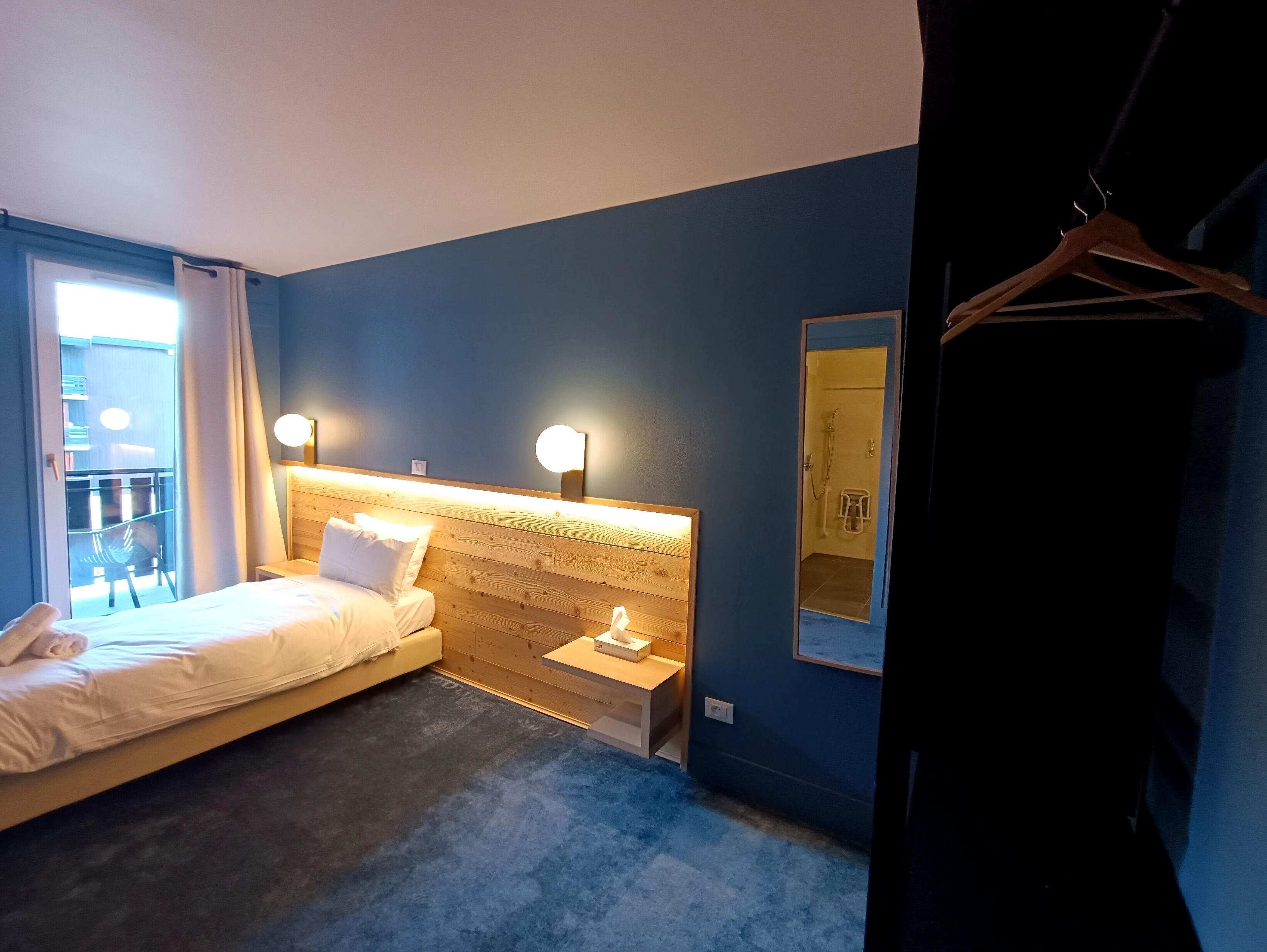 Habitación de hotel con cama, mesita de noche y espejo.