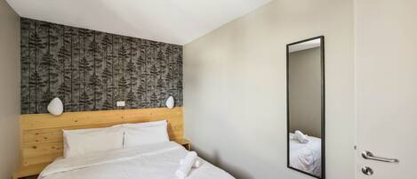 Habitación de hotel con cabecera de madera, un espejo grande y camas bien hechas con toallas.
