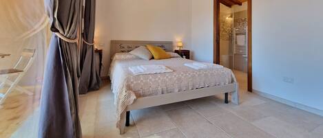 A bedroom with a bed, curtains, a chandelier, and an air conditioning unit.