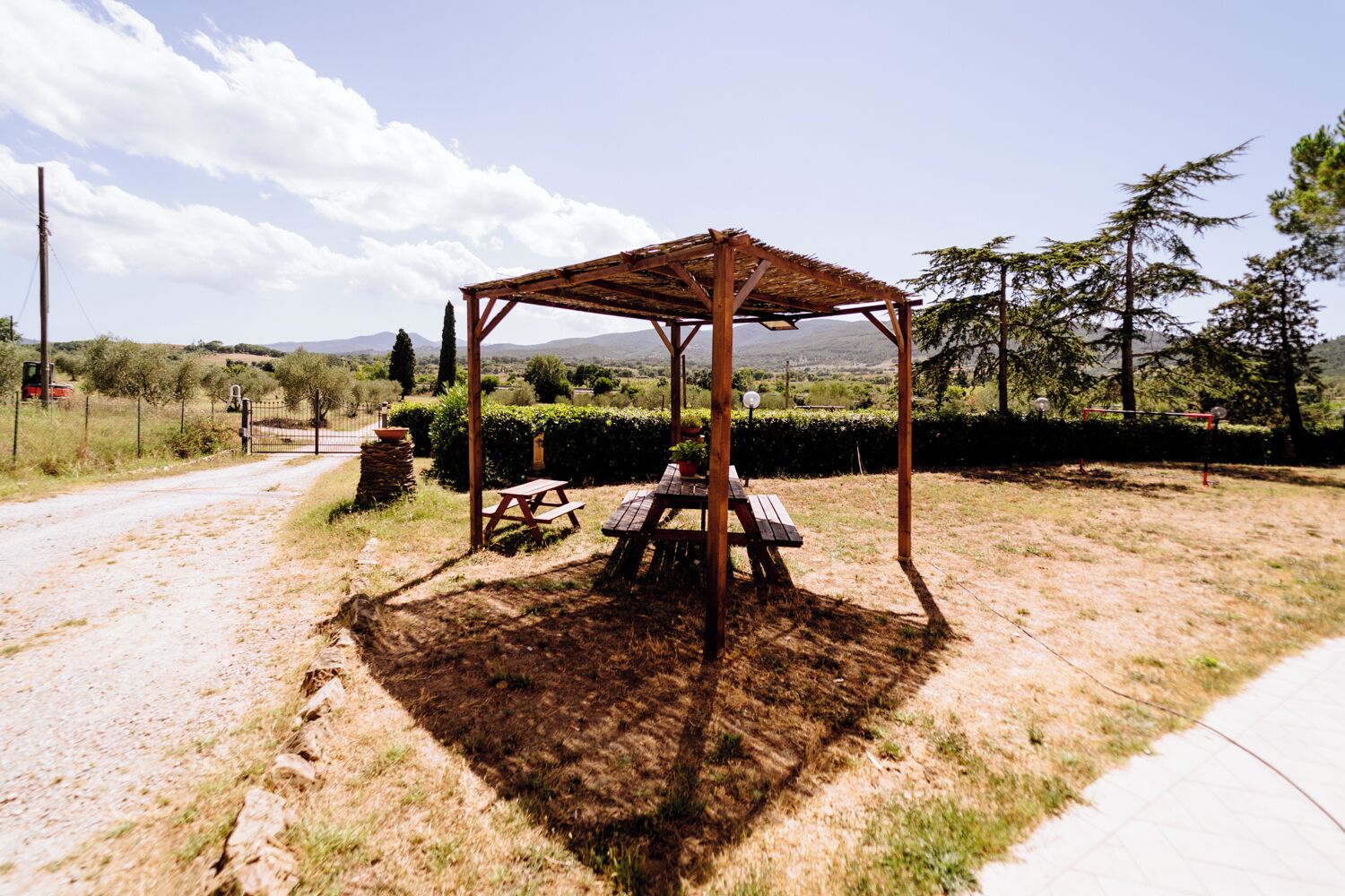 Un quiosco de madera rústico con mesas de picnic en un entorno rural.