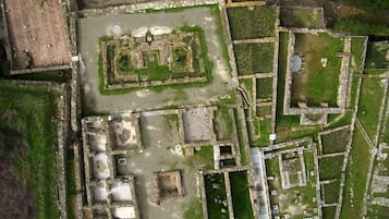 An aerial view of an ancient archaeological site with rectangular ruins, pathways, and open grassy areas.