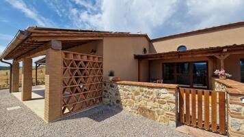 A building with a stone wall, wooden pergola, and a wooden fence.