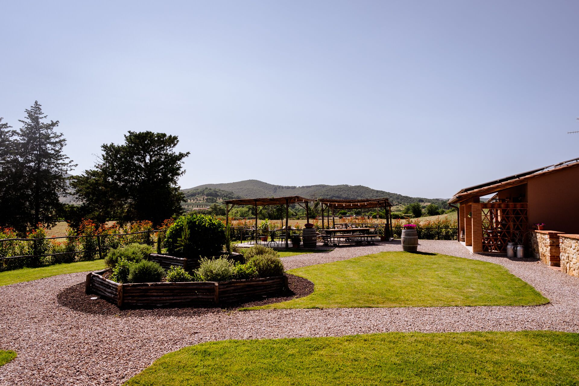 Un patio con mobiliario exterior, una pérgola y vistas a las colinas de fondo.