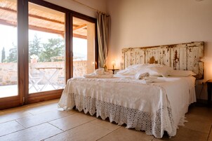 A bedroom with a large bed, a wooden headboard, a nightstand, and a window with a view of the outdoors.