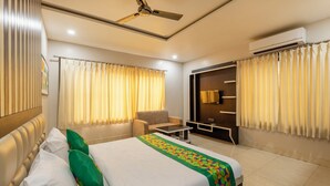 Ein Hotelzimmer mit einem Bett, einer Couch, einem kleinen Tisch, einem Deckenventilator und einer Klimaanlage.