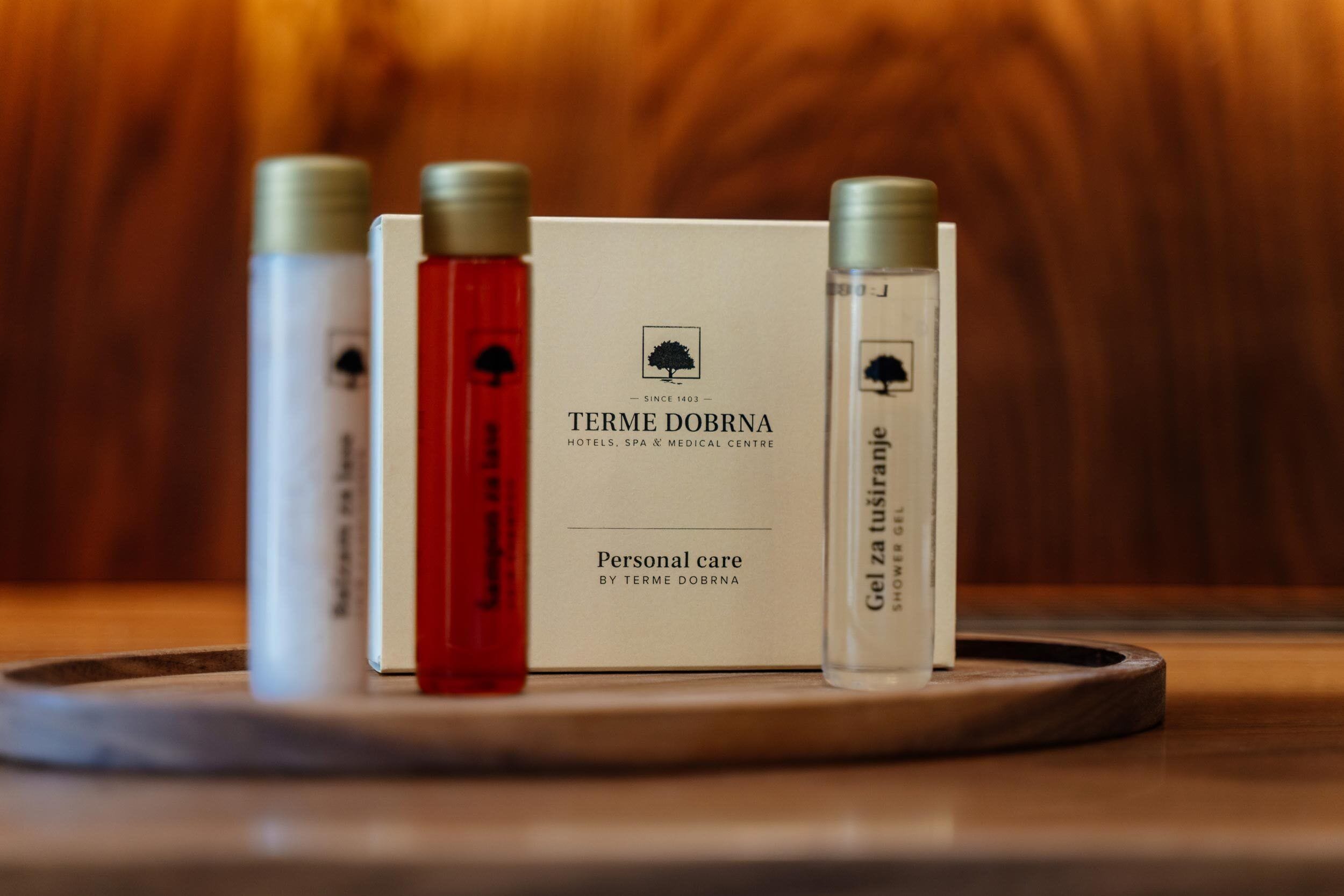 A tray with three bottles and a box labeled "TERME DOBRNA" on a wooden surface.