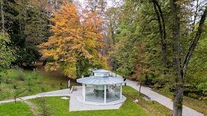 A gazebo in a park surrounded by trees with autumn foliage.