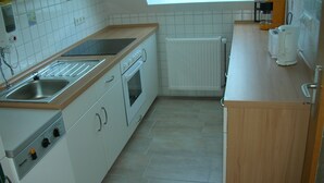 A kitchen with a sink, stove, oven, and a coffee maker. - Beautiful fine apartment with garden, meadow, view of water and land (Dornummersiel/Dornum)