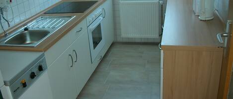 A kitchen with a sink, stove, oven, and a coffee maker.