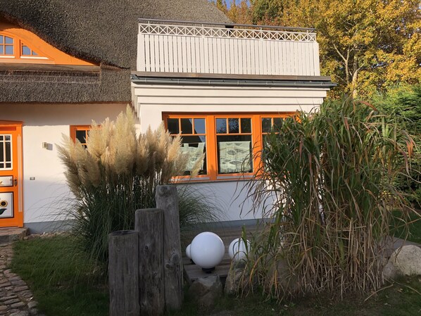 A house with a white exterior, orange accents, and a thatched roof.
