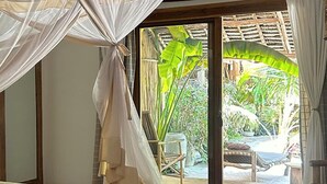 Una habitación con cama, dosel y vistas a un jardín a través de una puerta corredera.