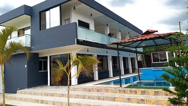 A modern two-story house with a swimming pool, stone steps, and a covered patio.